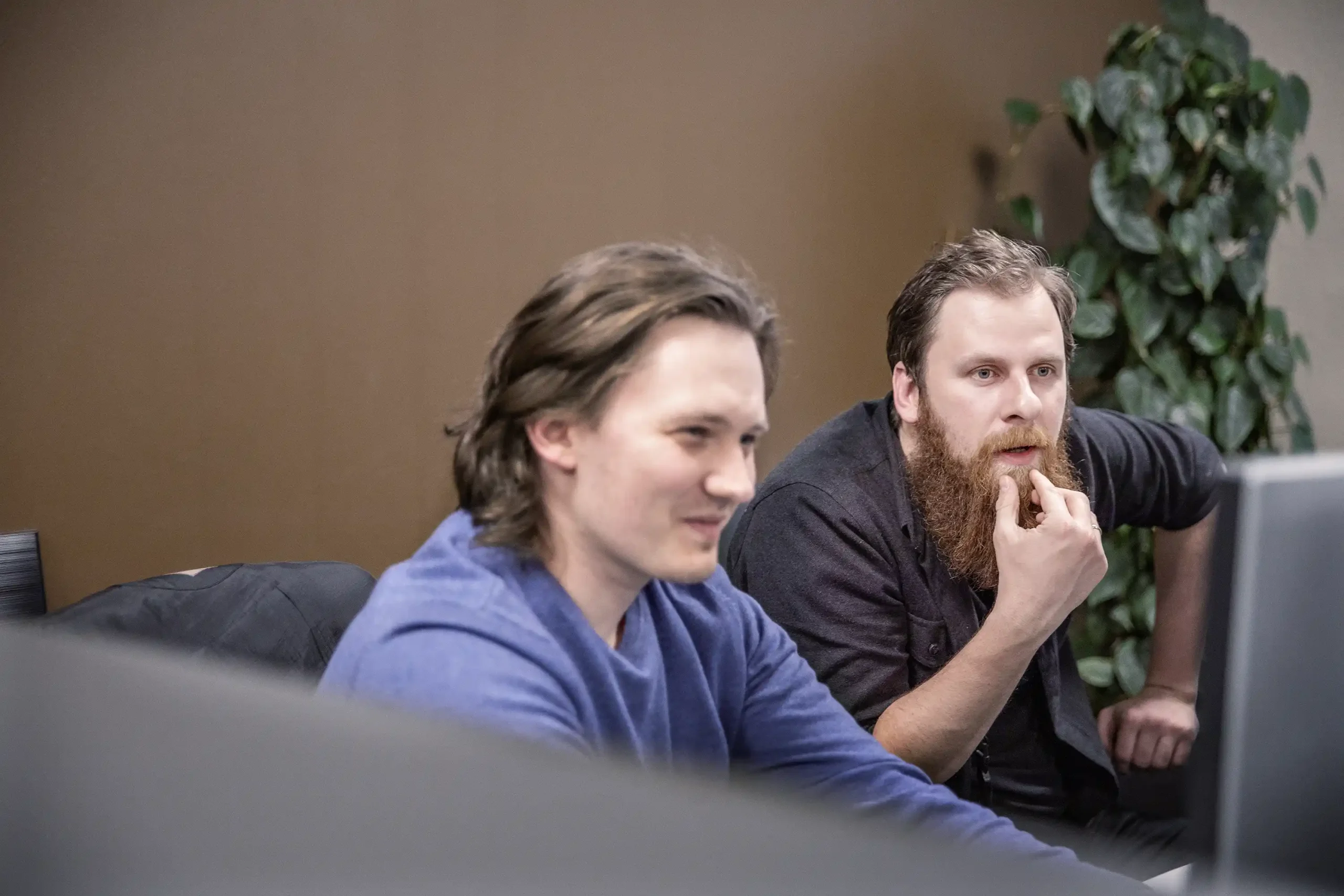 To ansatte ser på en skjerm sammen. En av de smiler, mens den andre ser konsentrert ut.